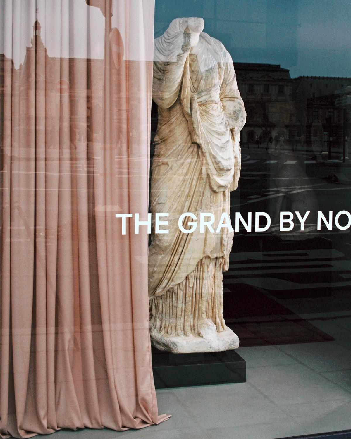 The Grand curtain in Old Rose draped near a marble statue with a window view at Galerie Chenel in Paris.