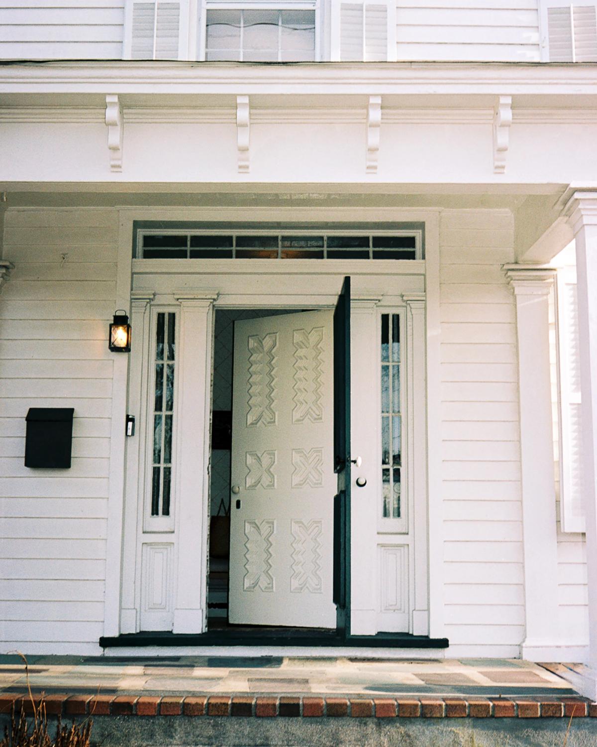 An image of a door opening to a lovely two-story white house in Bellport, USA.