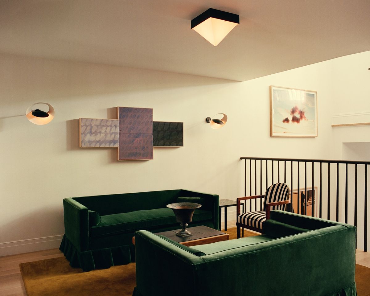 Grand in Pecan, das eine Sitzecke mit tiefgrünen Samtsofas und warmem Licht erdet – für ein gemütliches, zeitloses Ambiente.