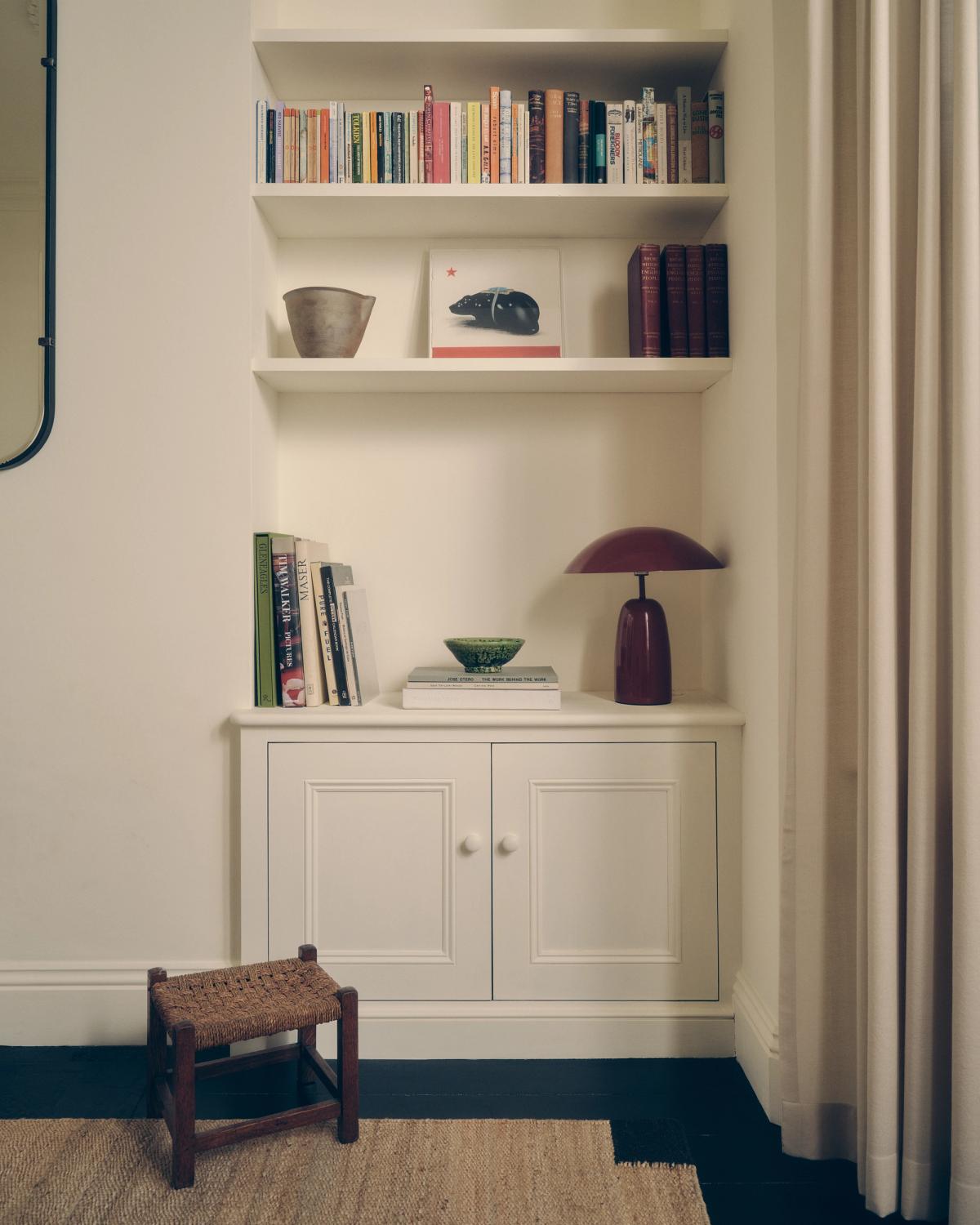 Jute-Teppich Corner Black, abgebildet neben einem Bücherregal.