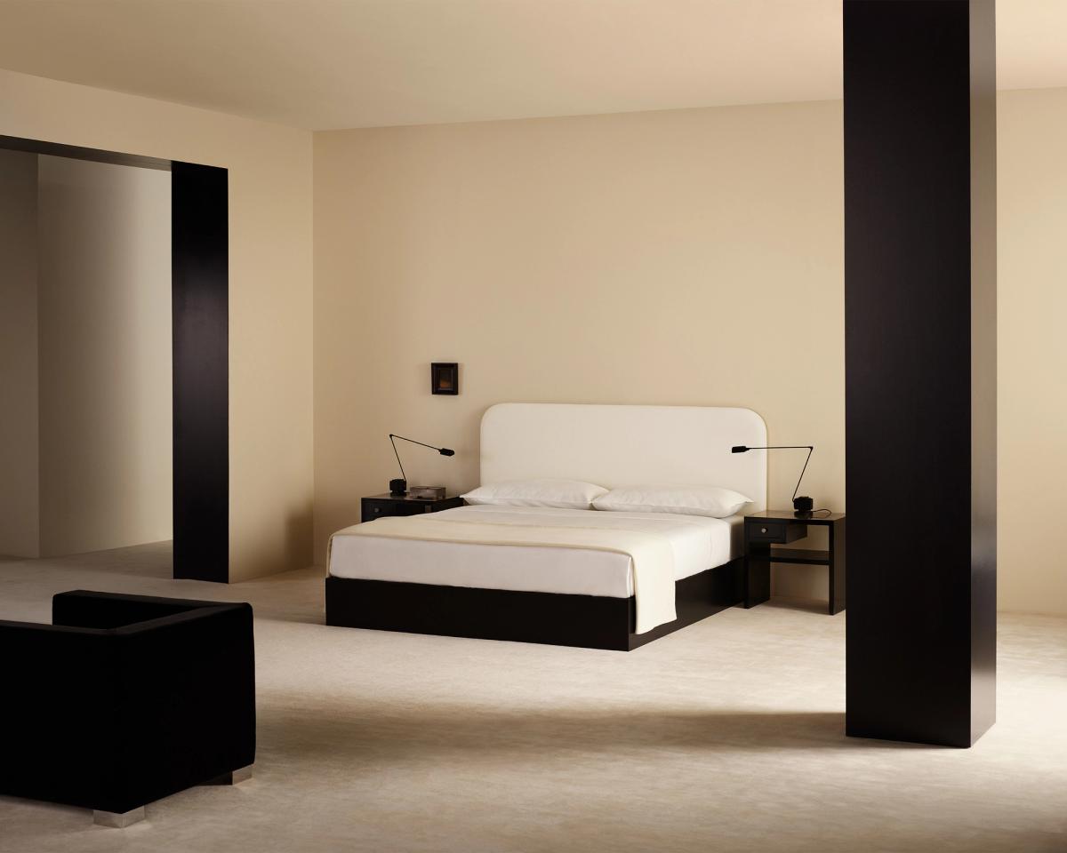 Minimalistisches Schlafzimmer mit klaren Linien, sanft cremefarbenen Wänden und weißer Bettwäsche aus der Nordic Knots Bedding & Decor Collection, kombiniert mit schwarzen Akzentmöbeln für eine moderne, ruhige Atmosphäre.