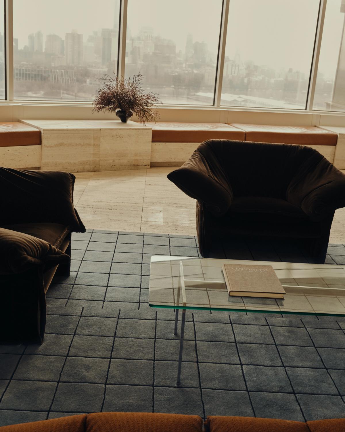 Mattan Grid i färgen Faded Blue/Black på marmorgolv, visad med två bruna fåtöljer i en skyskrapa i New York, USA.