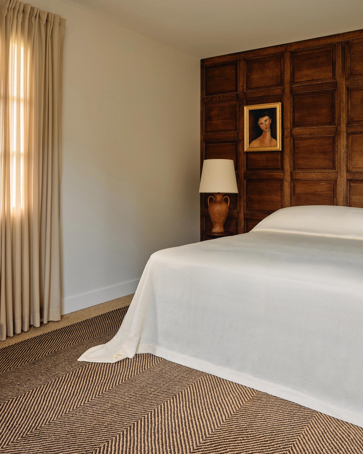 Jute Herringbone in Natural/Brown in a bedroom with wooden paneling, yellow curtains, and a white lamp.