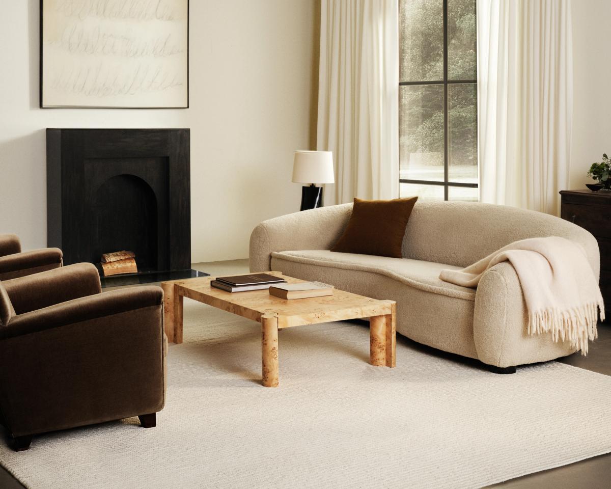 Tapis en laine tissé à plat Braid en Cream, photographié dans un salon avec une cheminée noire et un canapé blanc.