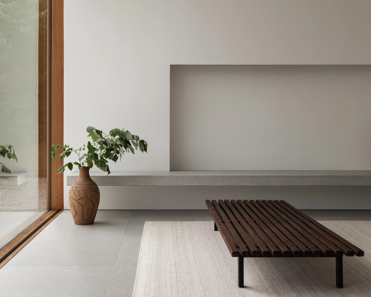 Tapis Zero Cream Mix photographié sous un banc en bois foncé dans un espace moderne et blanc.