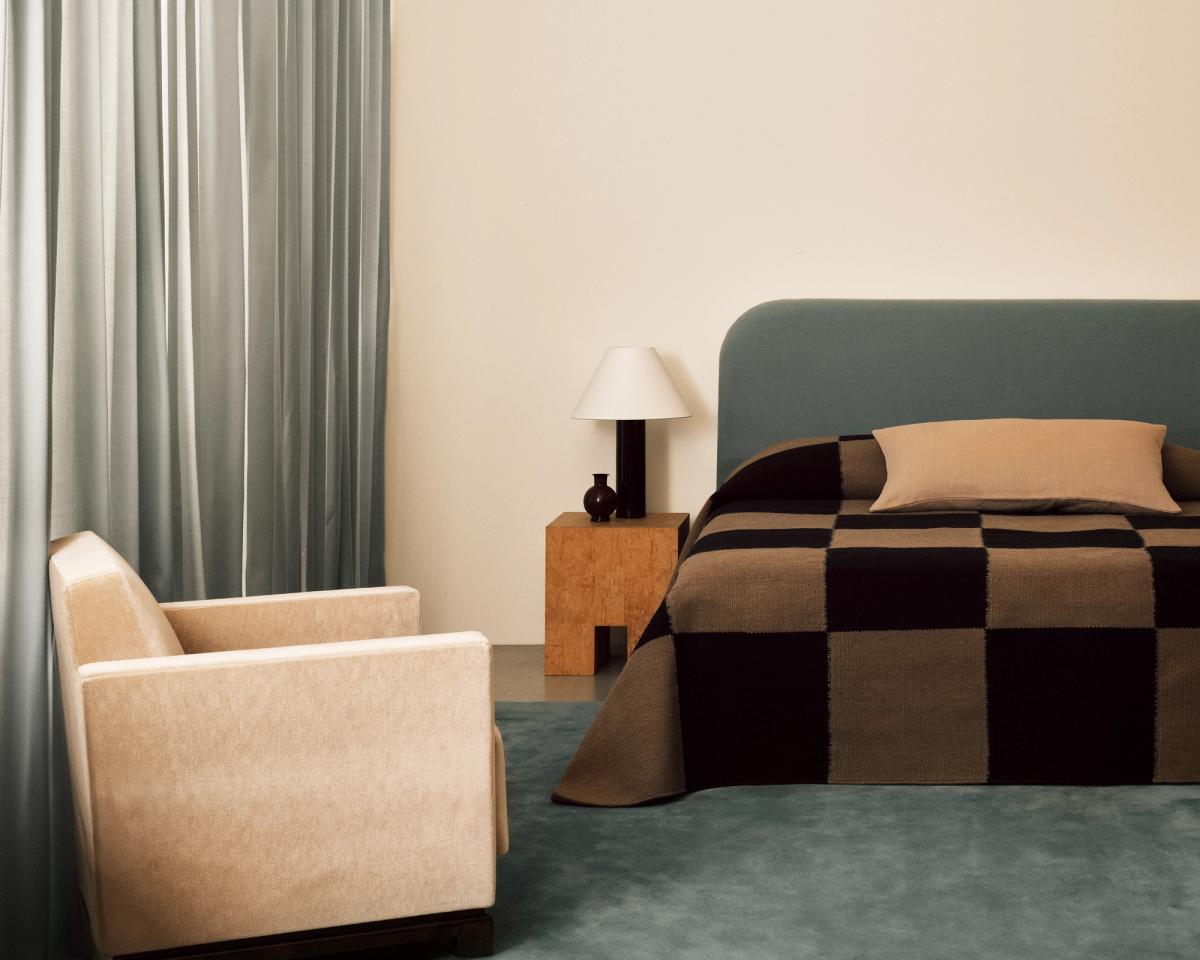 Les rideaux The Grand Pale Blue photographiés dans un salon moderne avec un mobilier assorti et le tapis tissé à plat Square Tobacco utilisé comme couvre-lit.