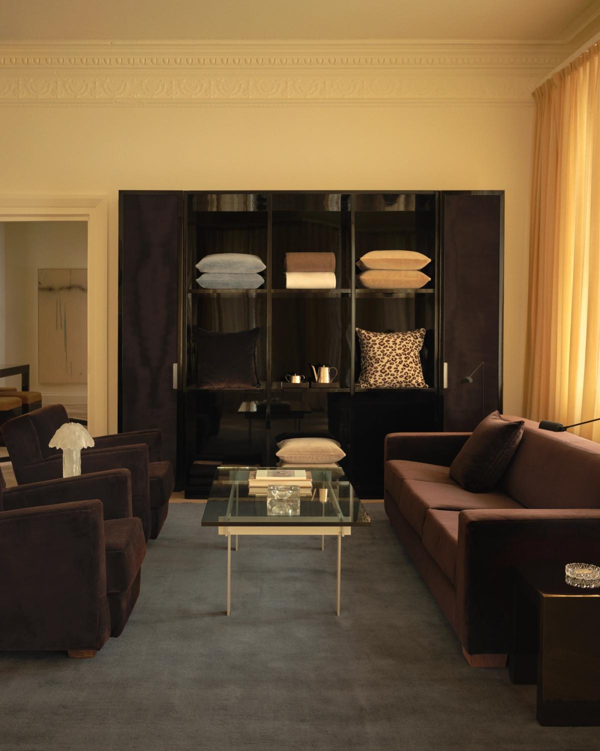 The Mohair rug in Slate Blue is shown in the Nordic Knots store on Mount Street in London, styled with dark velvet furniture, Leo curtains, and a glass coffee table for a refined, contemporary atmosphere.