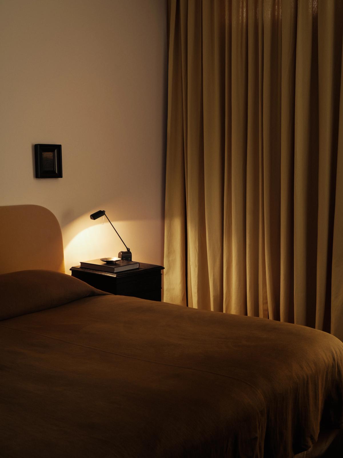 Nordic Knots The Blackout curtains in the color Leo pictured in a bedroom with rust orange bedsheets and a black nightstand.