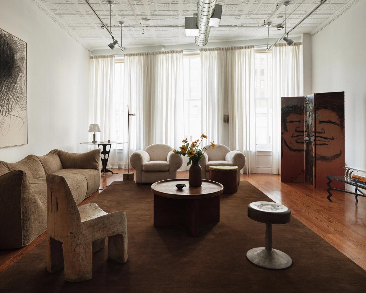 Plush wool rug Grand in Walnut pictured in a brightly lit living room with large windows and muted interior design details in Soho, New York.