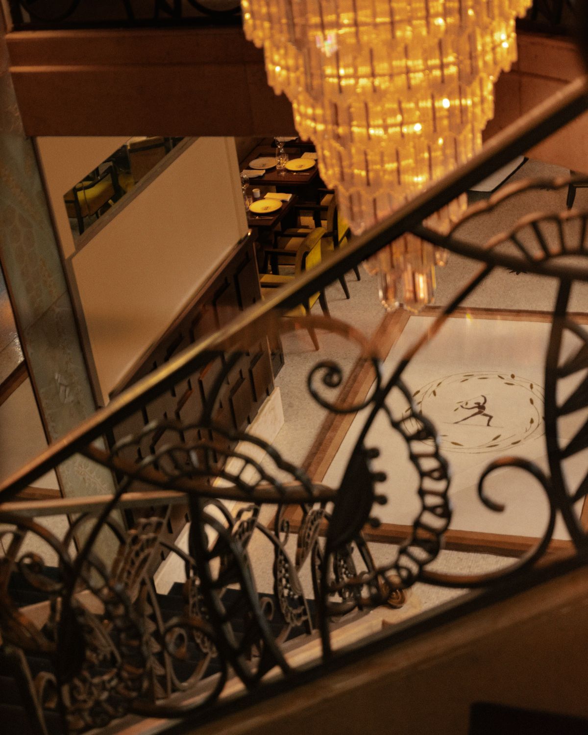 Plush wool rug by Parisian designer Fabrizio Casiraghi on the beautiful marble floor seen from an intricate staircase next to a large crystal chandelier in a restaurant in Paris, France
