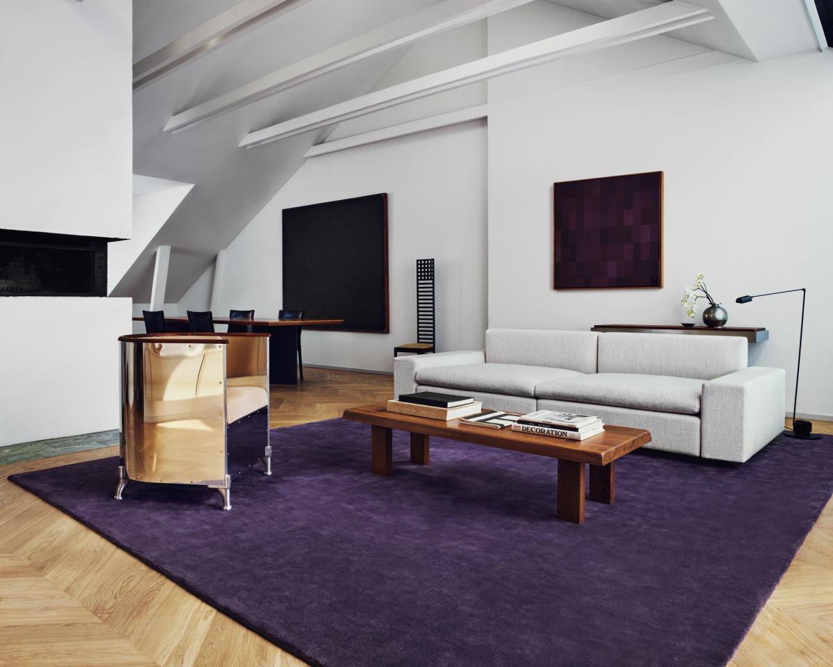 Flauschiger Wollteppich Grand in Lilac, abgebildet im Wohnzimmer einer Wohnung in Stockholm, mit Chromsesseln und grauem Sofa.