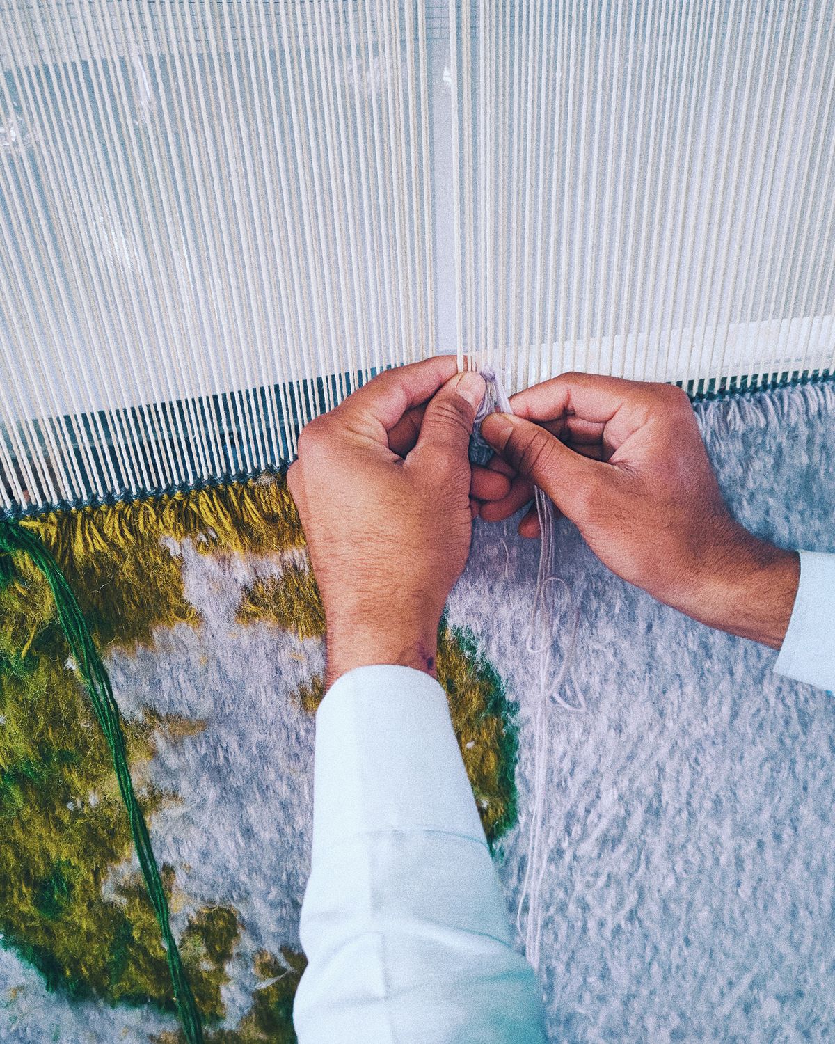 Hände beim Weben eines Climbing Vine-Teppichs am Webstuhl.