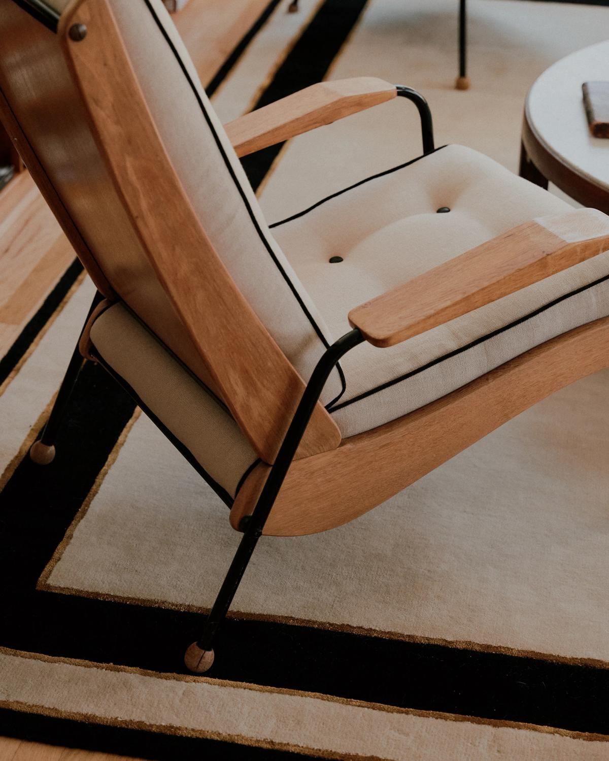 Närbild på den mjuka ullmattan Gild 01 med en träfåtölj.