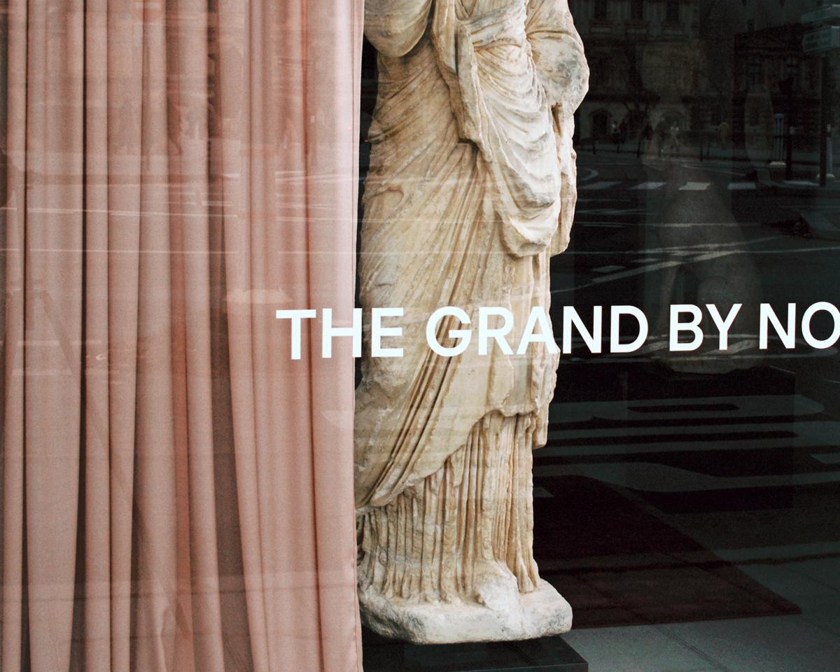 Der Vorhang Grand in Old Rose, drapiert neben einer Marmorstatue mit Fensterausblick in der Galerie Chenel in Paris.