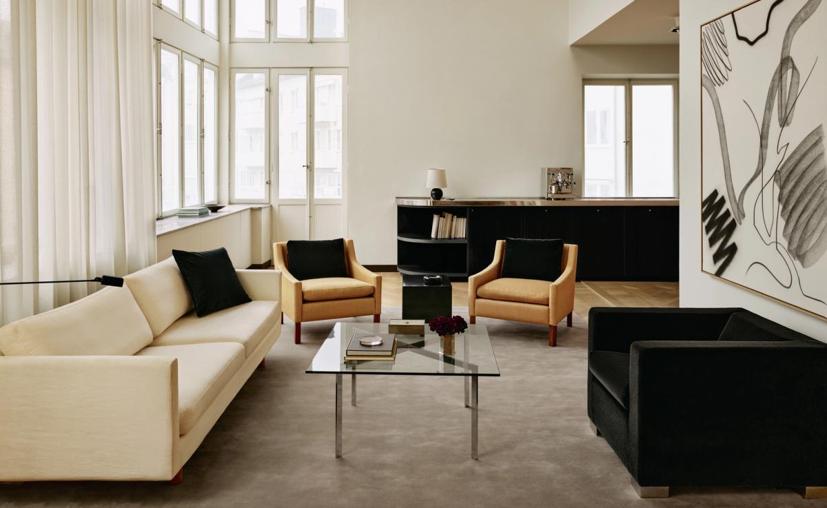 Grand – Warm Gray lägger en mjuk och grundande bas i detta ljusa och strukturerade vardagsrum. Den sammetlika texturen balanserar kontrasten mellan krämvita, ockragula och svarta möbler, och binder samman djärva silhuetter med stillsam elegans.