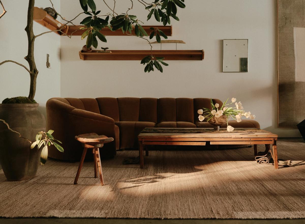 Jute rug Edge Cream pictured in a cozy livingroom with neutral colored furniture and large plants at studio WAS in New York.