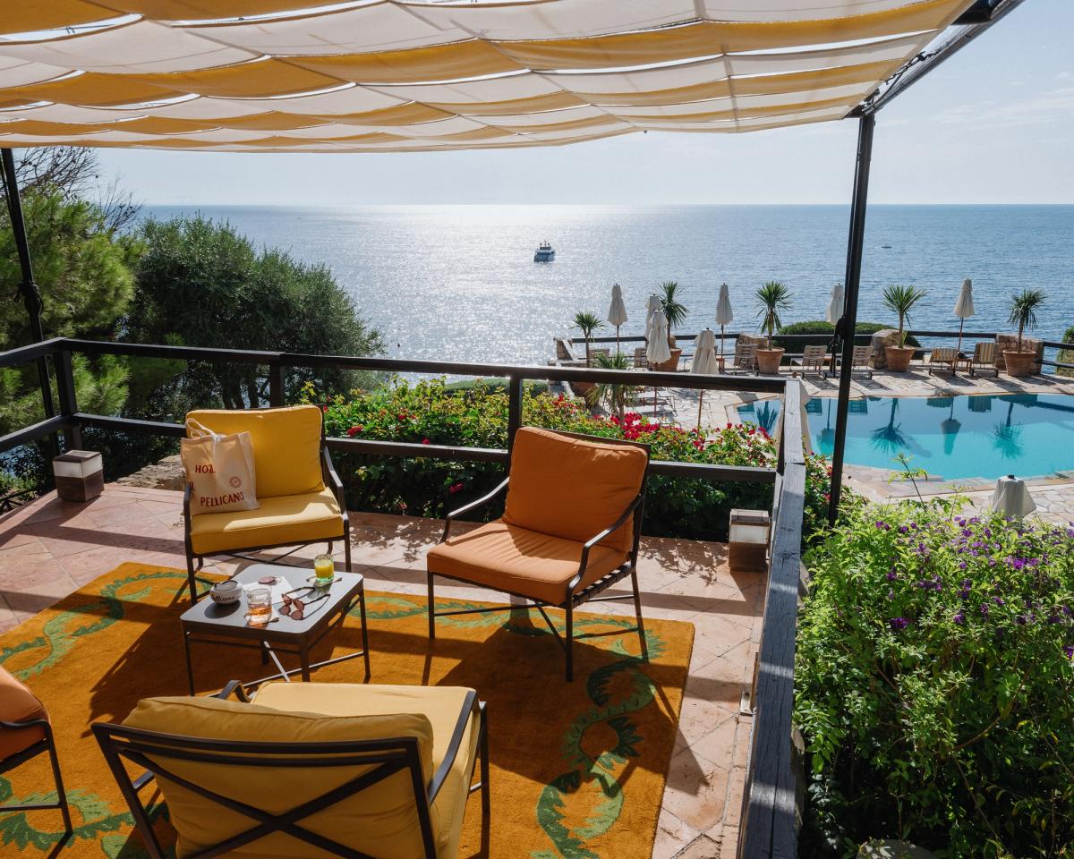 Tapis Climbing Vine ISSIMO photographié sur un balcon bordé de buissons, surplombant une piscine et la mer à l’hôtel Il Pellicano en Italie.
