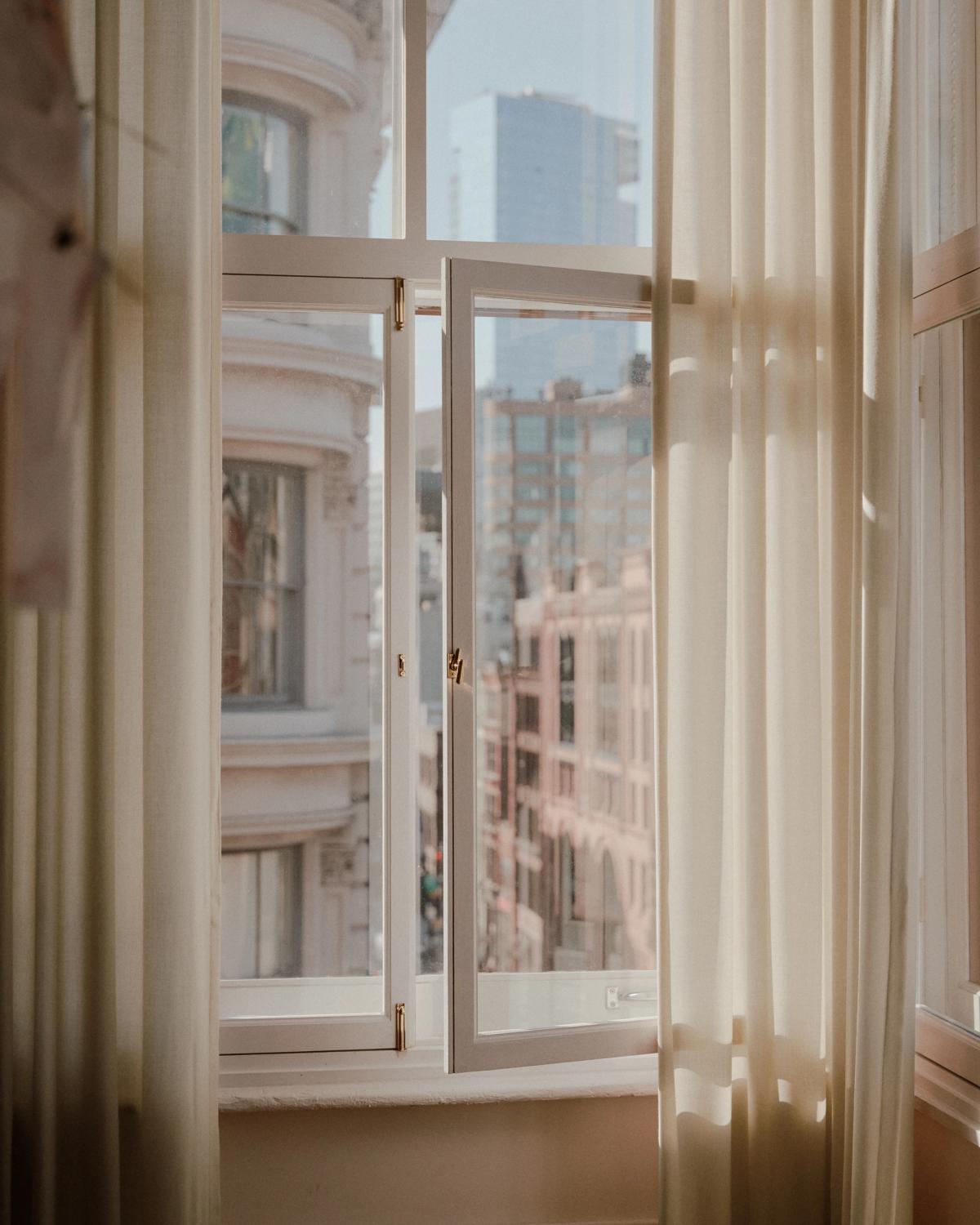 Bild av ett öppet fönster med ullgardinerna The Grand dragna åt sidorna.