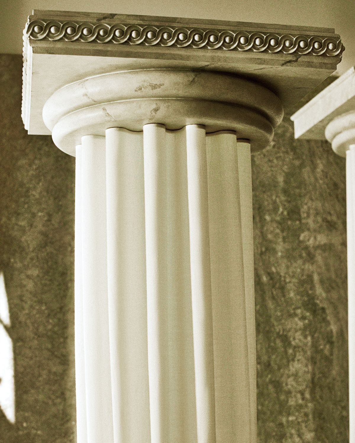 The Grand curtains on an ancient greek style pillar in the Stockholm Flagship with the light shining in through the windows onto the green marble interior.