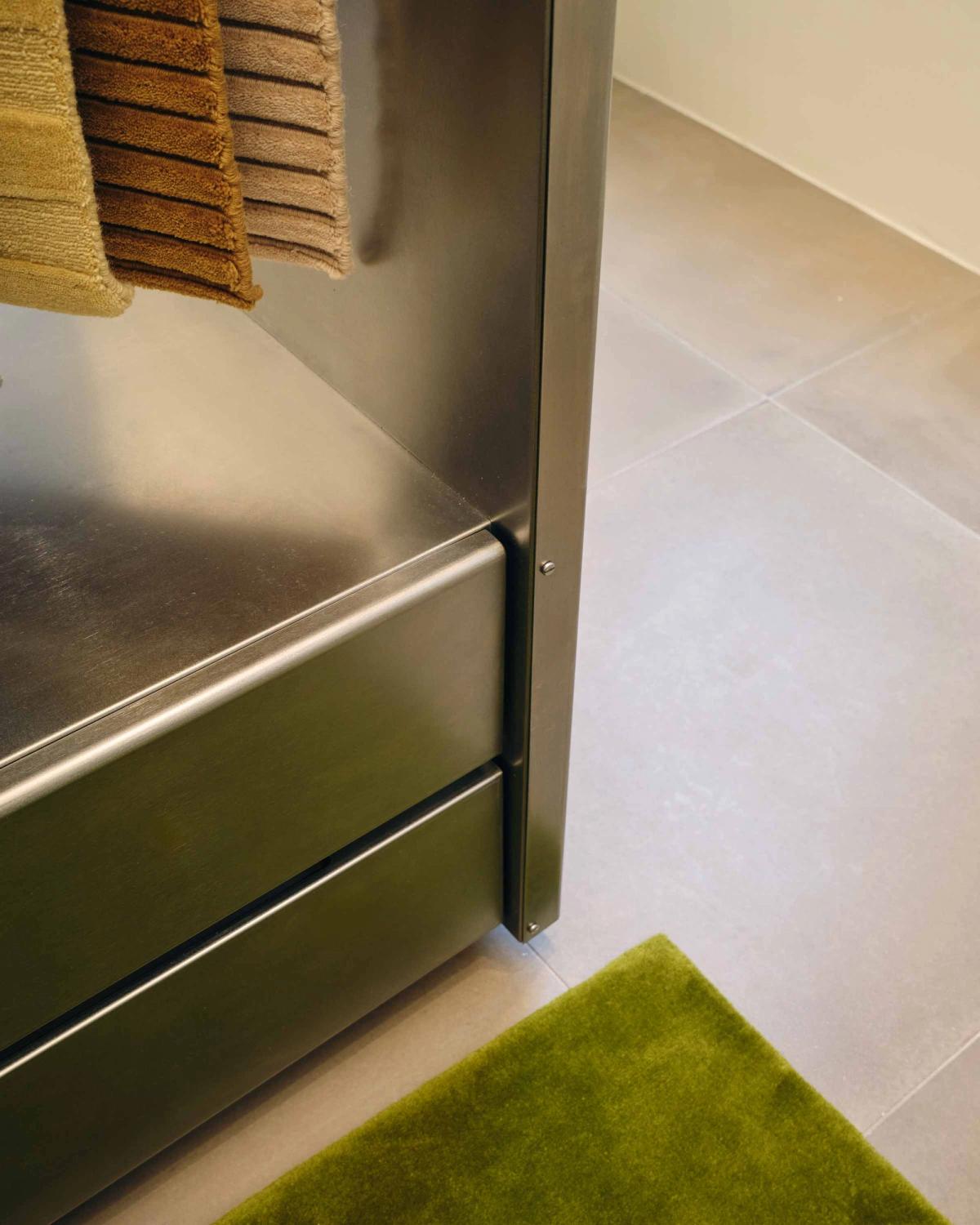 Close up shot of plush wool rug Grand Milano Green and the metal racks for the rug samples.