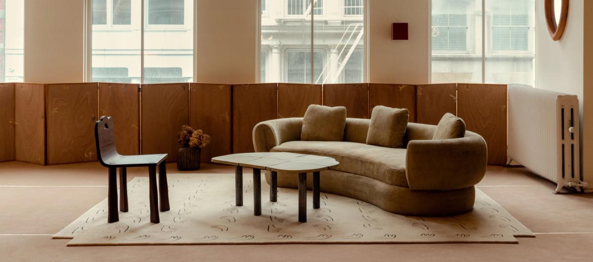 Vardagsrum med rundad soffa och mattan All Hands – Beige.