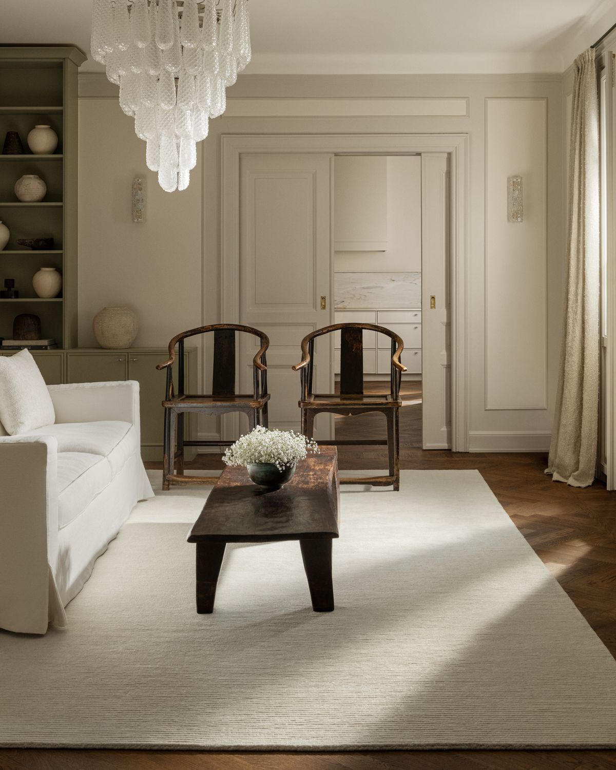 Park rug in color Dusty White displayed in a sunny turn of the century apartment. Styled with vintage furniture and ceramics.