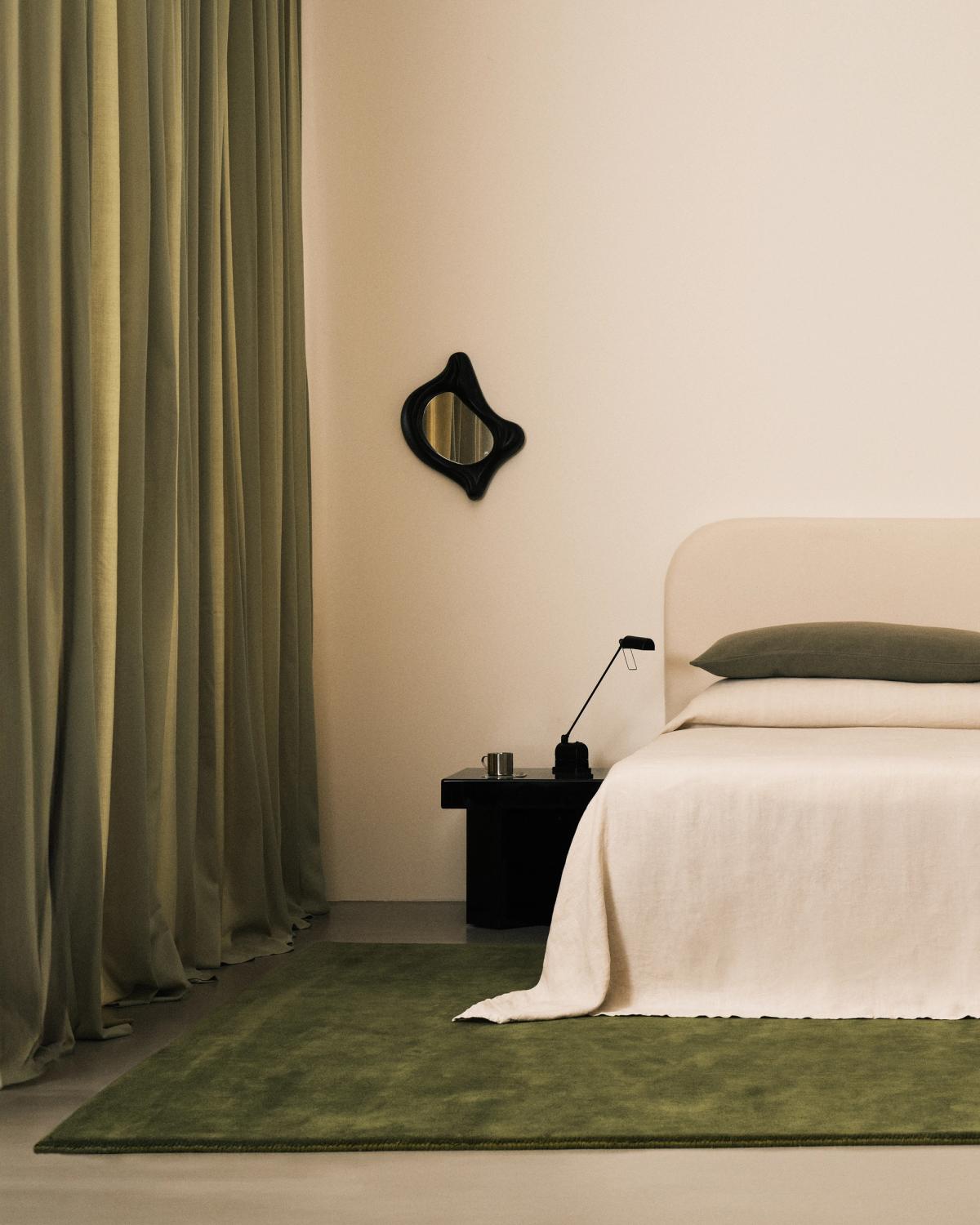 Gardinerna The Grand i färgen Pale Green fotograferade i ett rofyllt sovrum med den mjuka ullmattan Grand i färgen Moss och en mjuk vit säng.