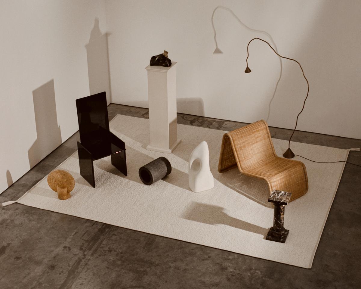 An image of Bouclé in Cream in Monument store in London. On top of the rug sits a few sculptural furniture, creating beautiful shadows on the rug.