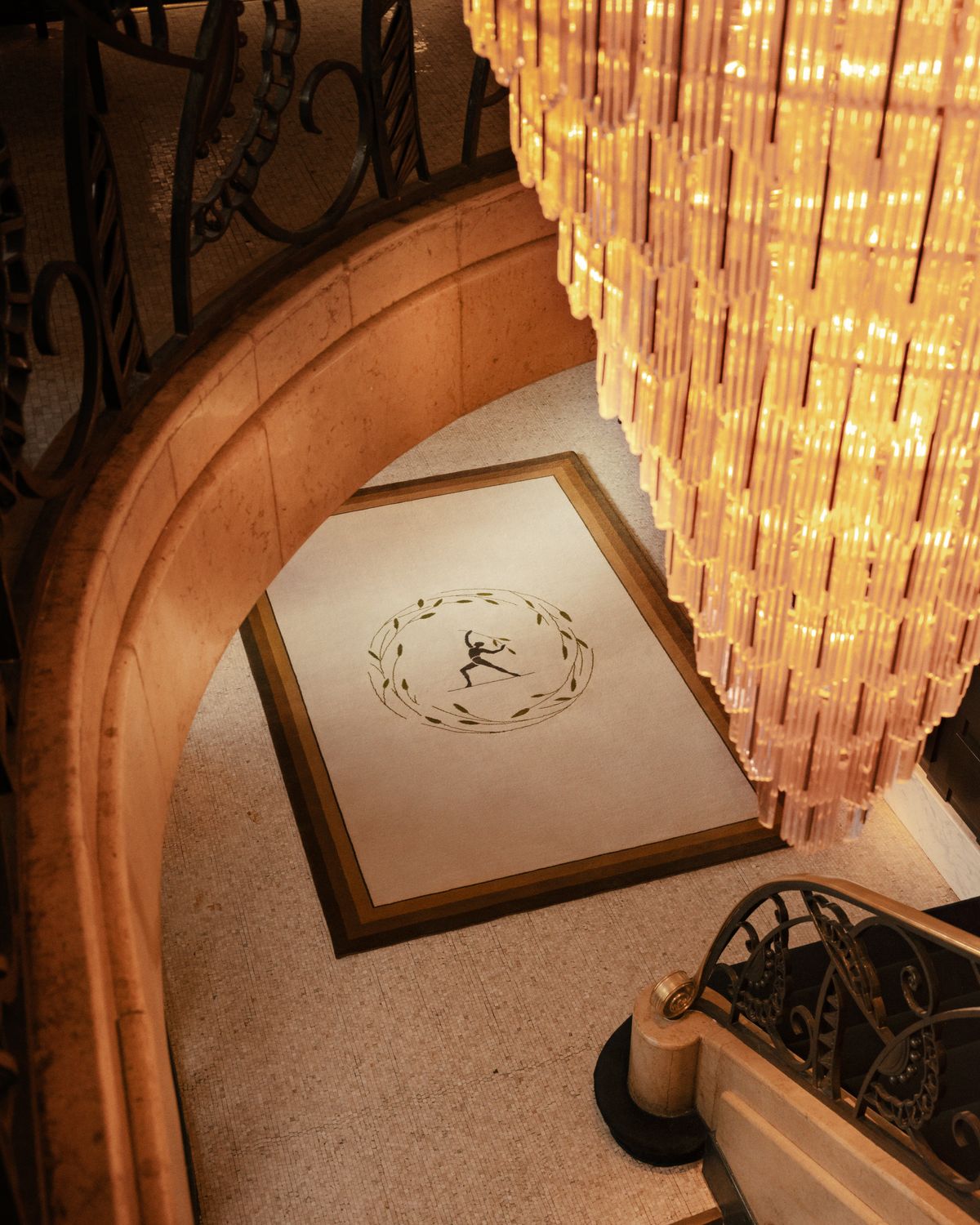 Plush wool rug designed by Parisian designer Fabrizio Casiraghi on a marble floor next as seen looking down from a beautiful staircase next to a large chandelier in Paris, France