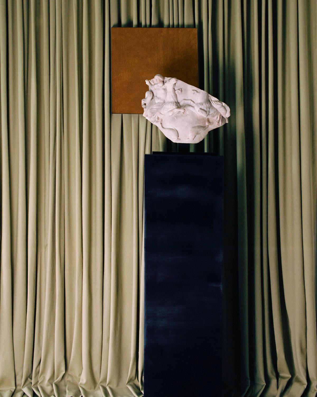 The Grand curtain in Pale Green and a painting of the Grand rug in Leo displayed behind a marble statue at Galerie Chenel in Paris.