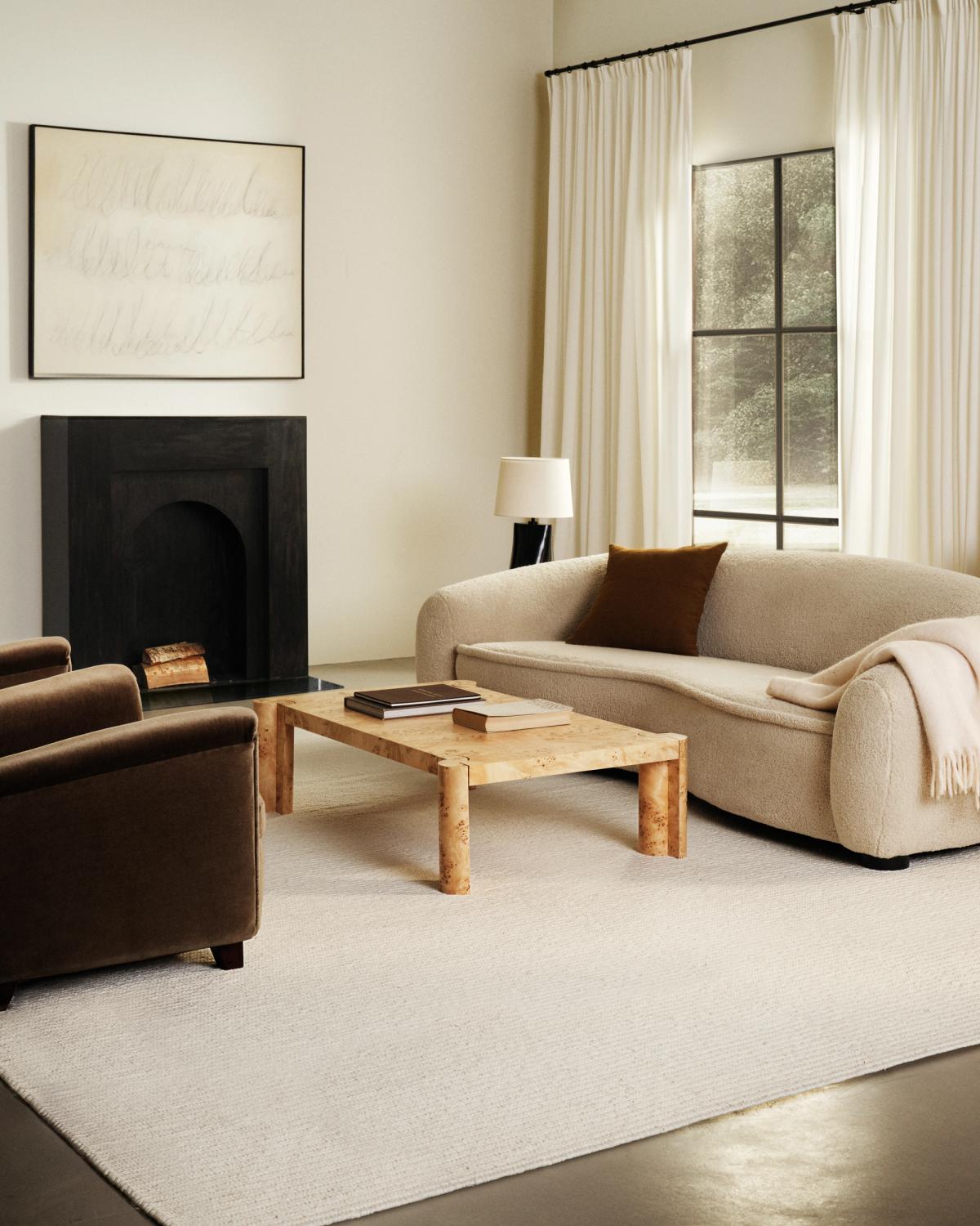 Flatweave wool rug Braid in Cream pictured in a living room with a black fireplace and white sofa.