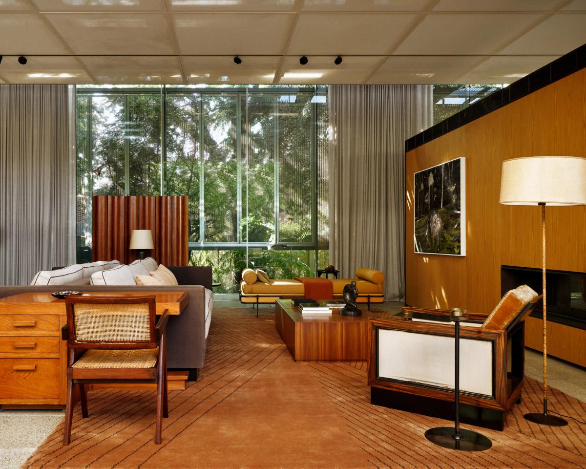 Le tapis Indore en Terracotta, mis en scène dans un salon à São Paulo avec de grandes baies vitrées, du mobilier mid-century, des boiseries chaleureuses et une lumière naturelle douce.