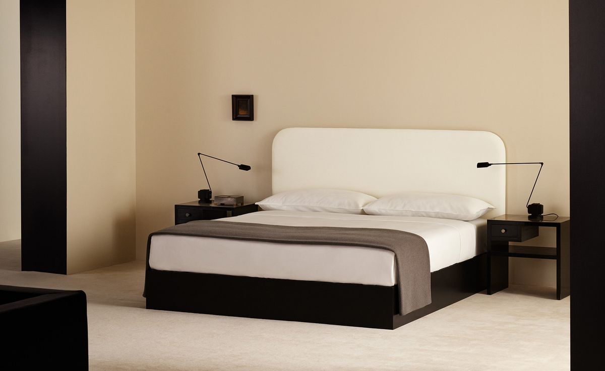 Klares, weißes Bettwäsche-Set mit einem Heritage-Überwurf in Taupe, kombiniert mit dem Signature-Kopfteil in Warm White für ein ruhiges, tonales Schlafzimmer.