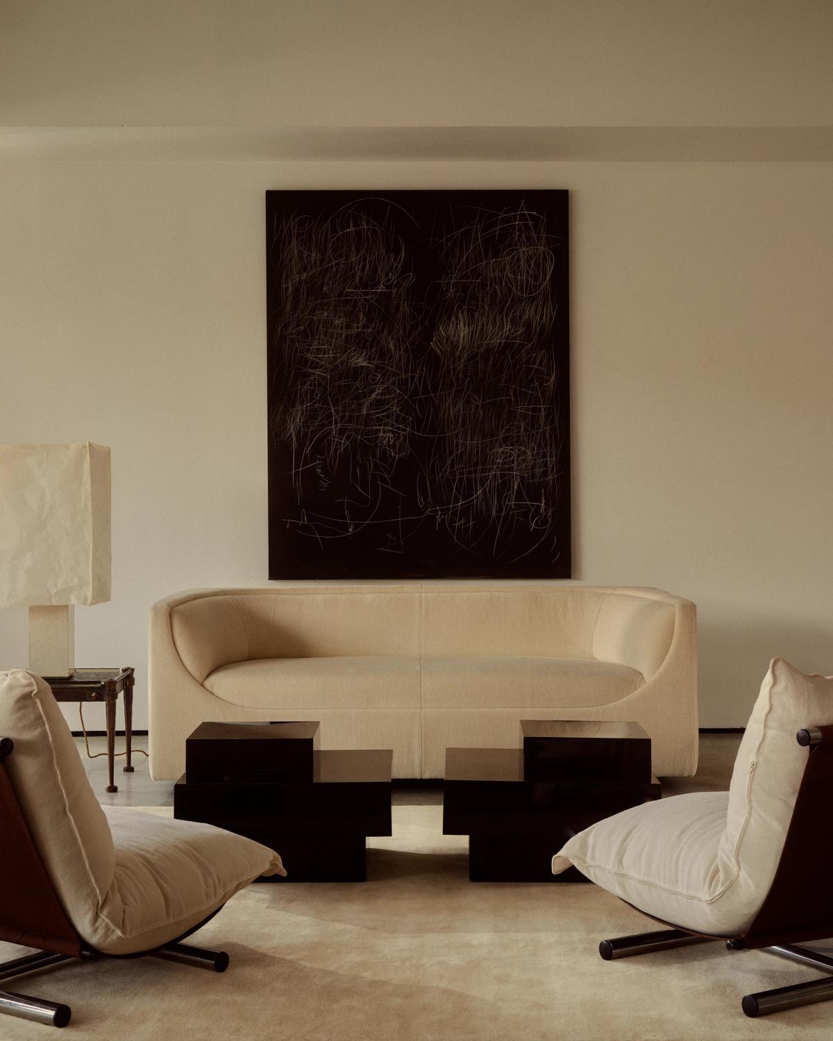 Mattan Grand i färgen Butter, i ett ljust vardagsrum med moderna, skulpturala möbler. Skapar en noggrant kurerad miljö.