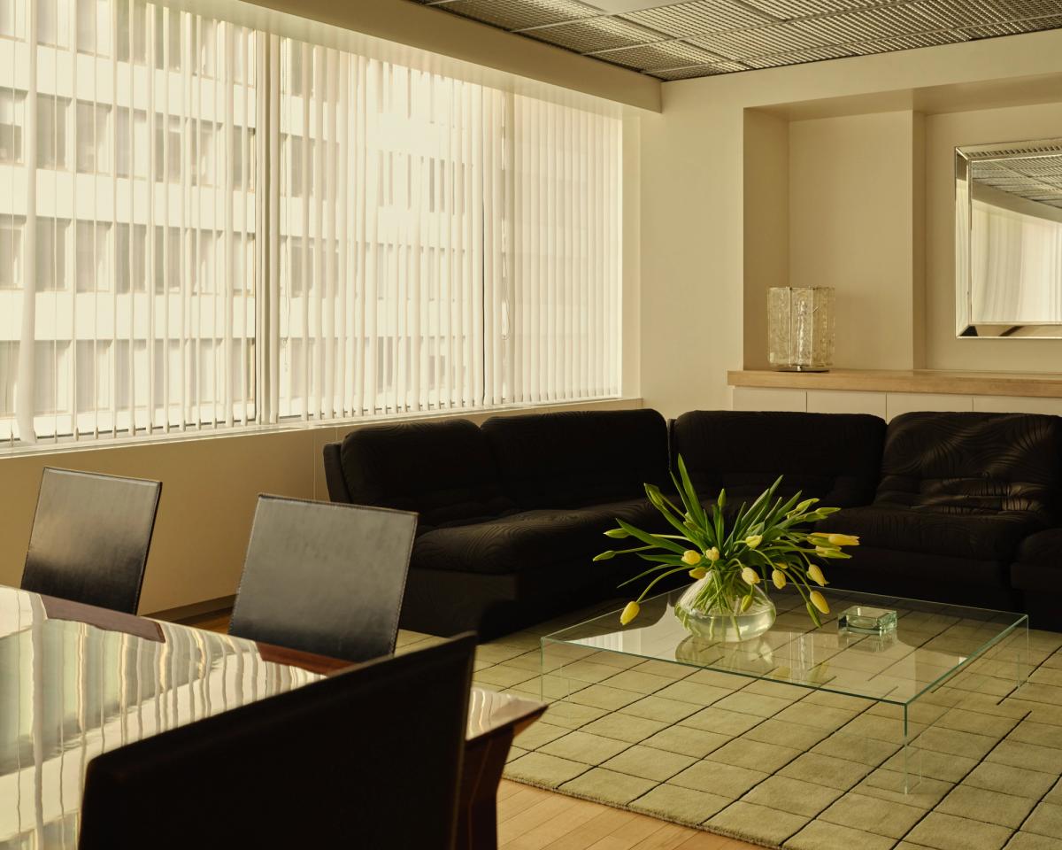 Mattan Grid i färgen Pistachio/Black tillför subtil struktur och mjukhet i en modern lounge med mörka sammetsmöbler, glaselement och stadsljus filtrerat genom lodräta persienner.