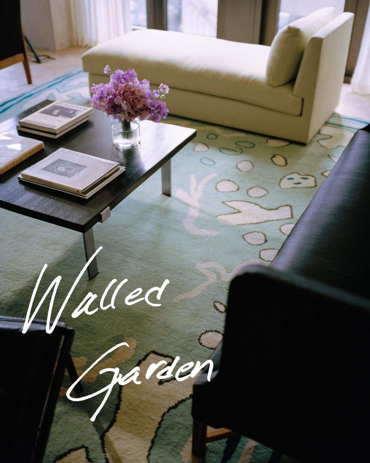 Giverny in Green in a bright living room with large windows. Styled with a black coffee table, a light chaise longue and a dark sofa.