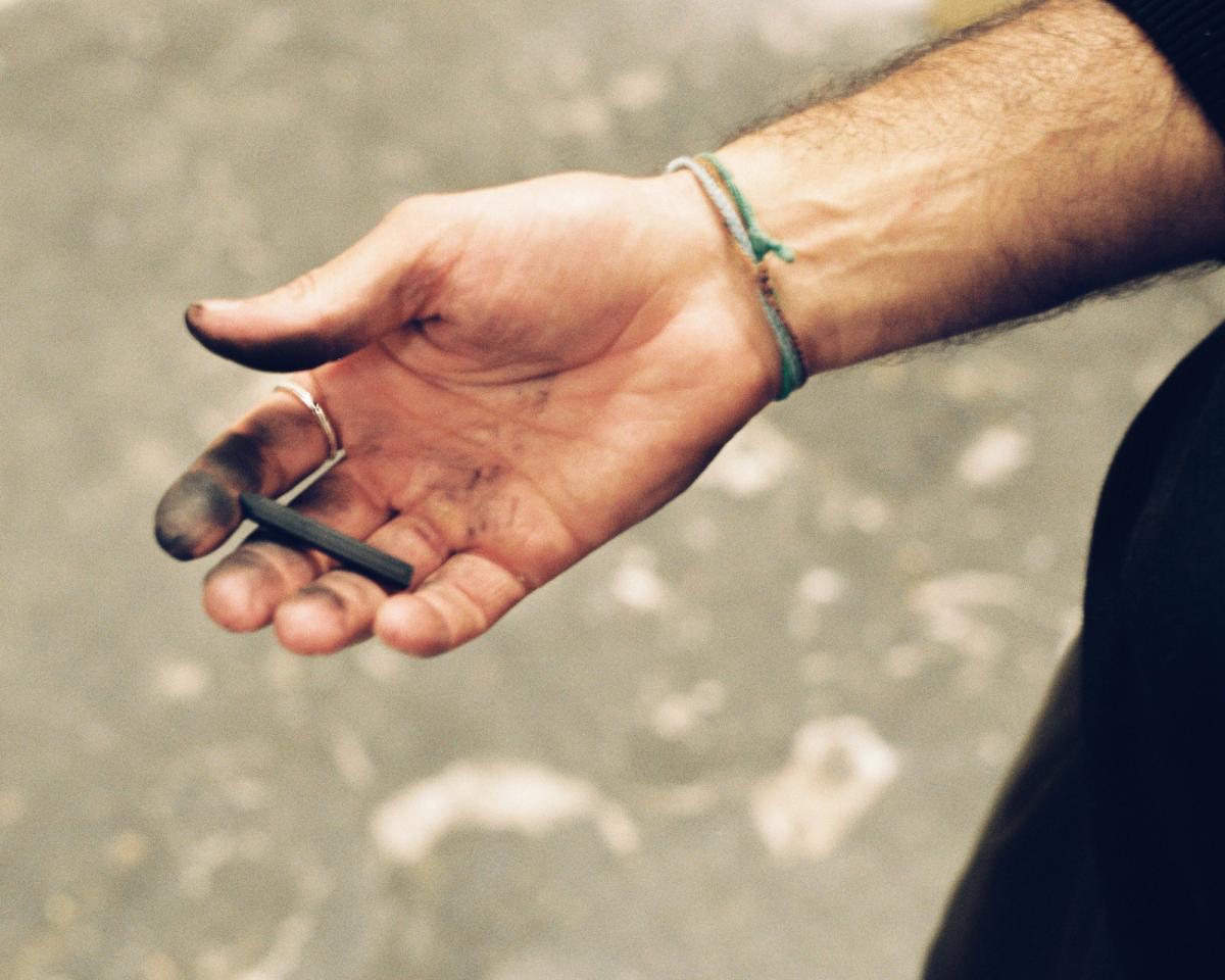 Die Hand von Aythamy Armas, die einen Kohlestift hält.