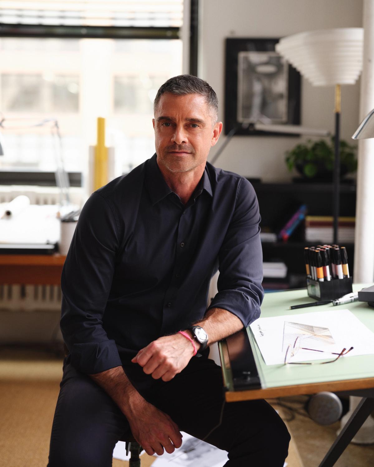 En formgivare sittande i en studio i Soho, New York, omgiven av skisser, verktyg och materialprover.