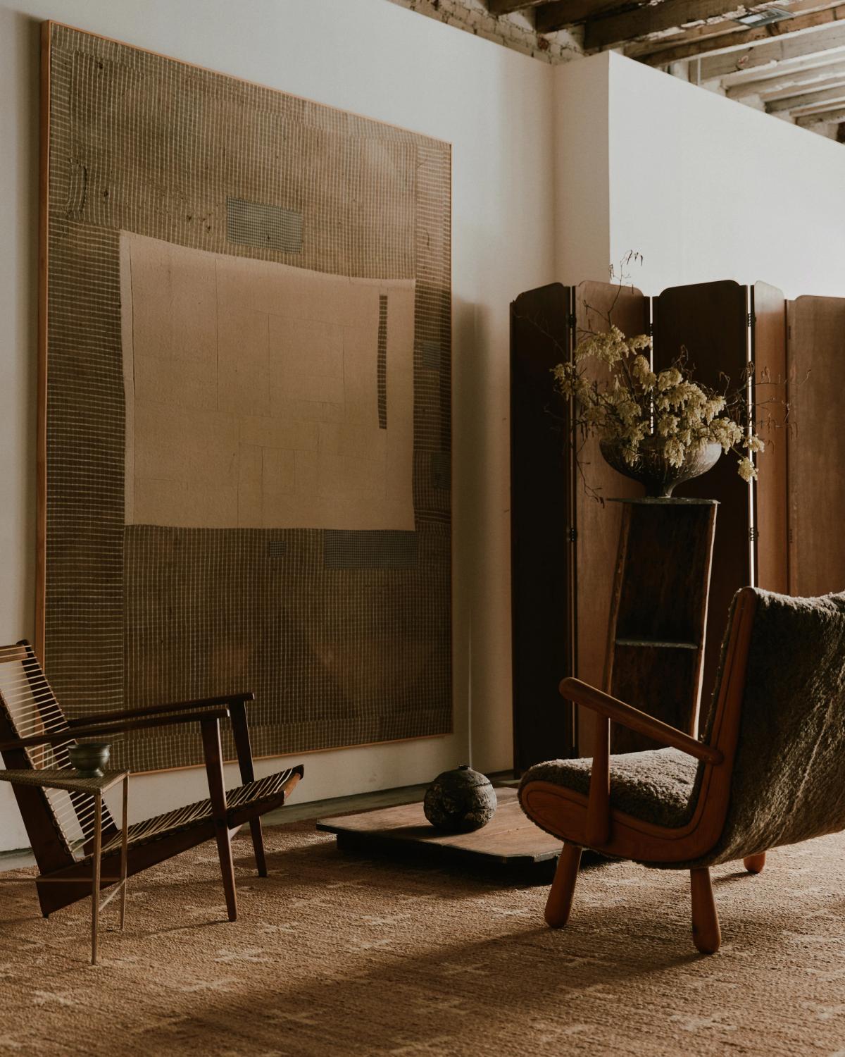 Jute rug Cross Cream photographed in a zen sitting area with wooden furniture and a large painting at studio WAS in New York.
