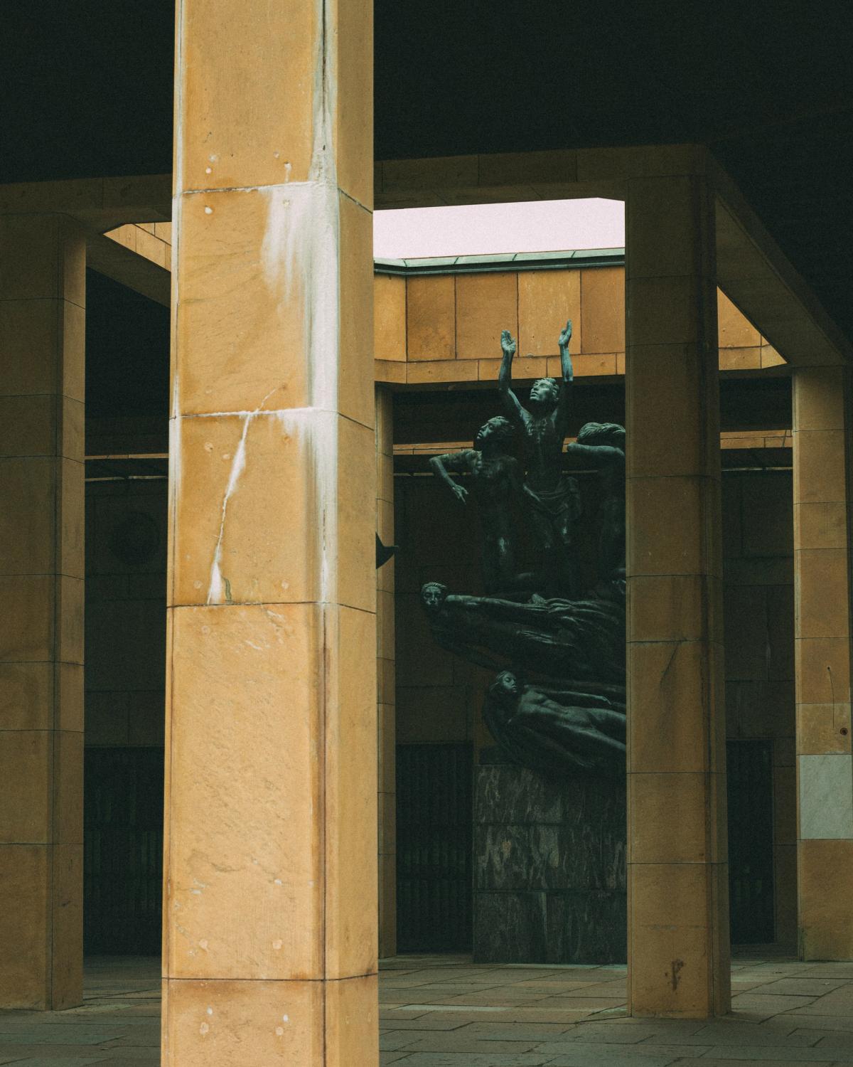 Photo d'une statue en métal au centre de piliers en pierre carrés.