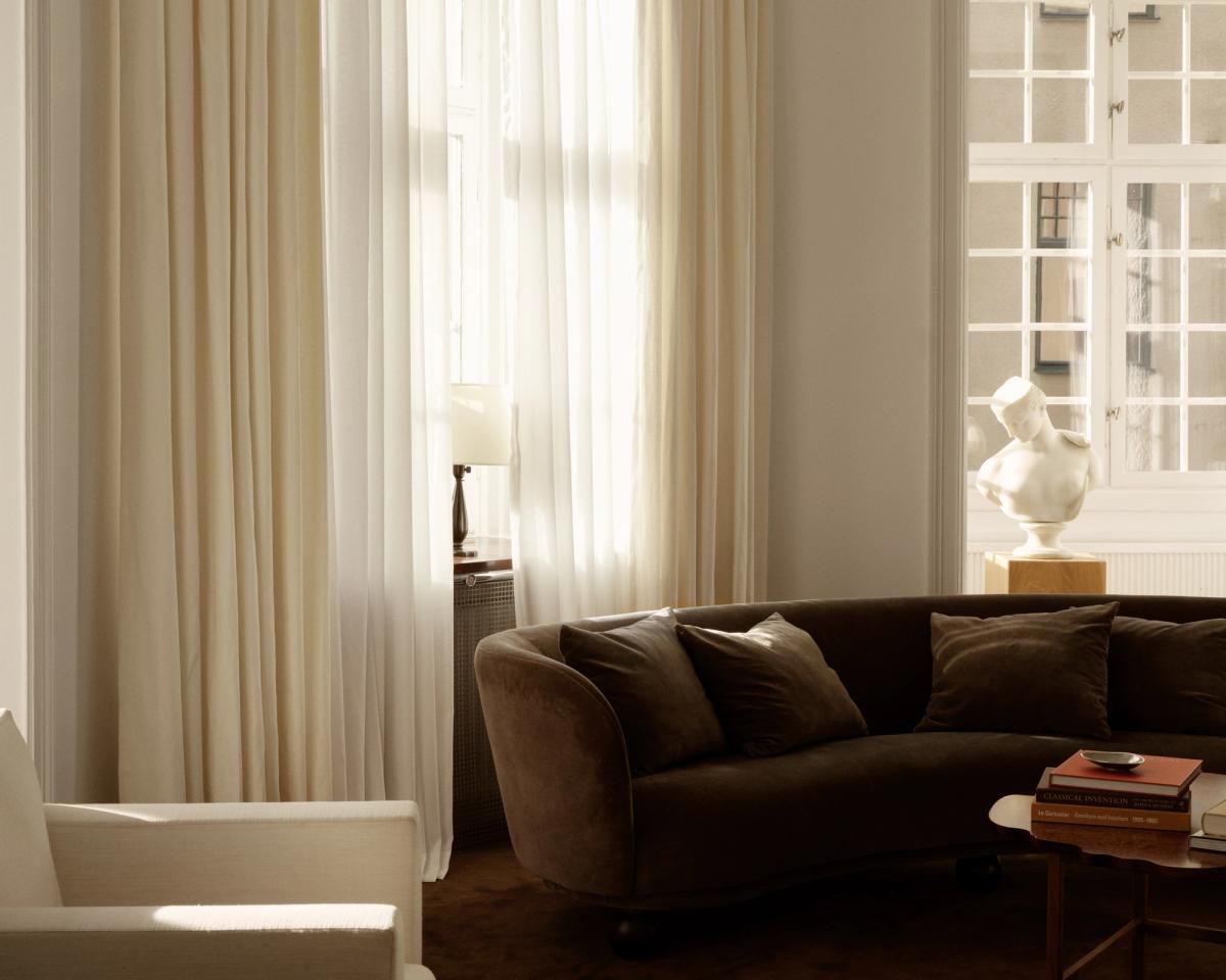 The Sheer curtains displayed in a living room with a brown curved sofa in Stockholm, Sweden.
