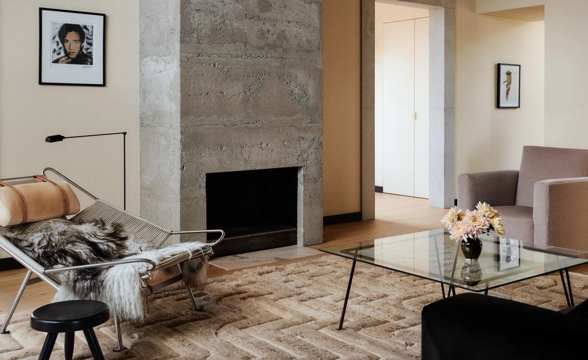 Boho 02 – Taupe Mix-mattan i ett varmt vardagsrum med betongspis och moderna möbler. Inredd med ett soffbord i glas, en loungestol och neutrala toner.