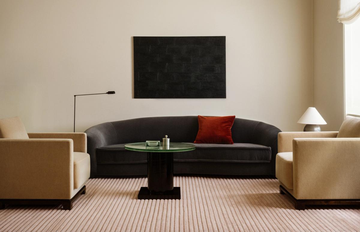 Teppich Park 02 in Rose – ein weich rosafarbener Teppich mit tonalen Längsstreifen, der ein modernes Wohnzimmer mit skulpturalen Sitzmöbeln und einem runden Glastisch ergänzt.