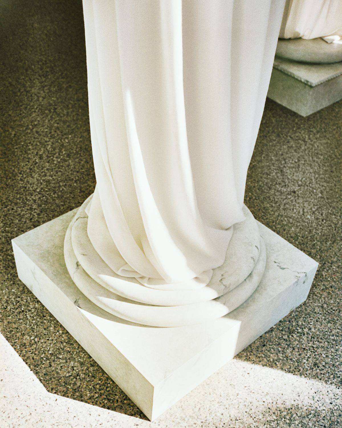 The Grand curtains photographed on a pillar on the green marble floor in the Stockholm Flagship with the light shining in through the windows.