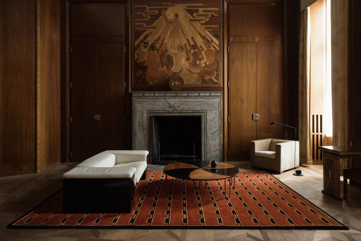 Plush wool rug Gild 02 pictured in an elegant living room with tall wood walls and a grand marble fireplace.