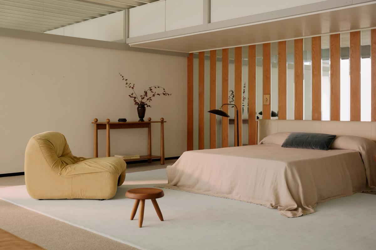 Plush wool rug Grand in Powder Blue photographed in a modern Los Angeles bedroom with a mustard tone sitting chair and beige bed.