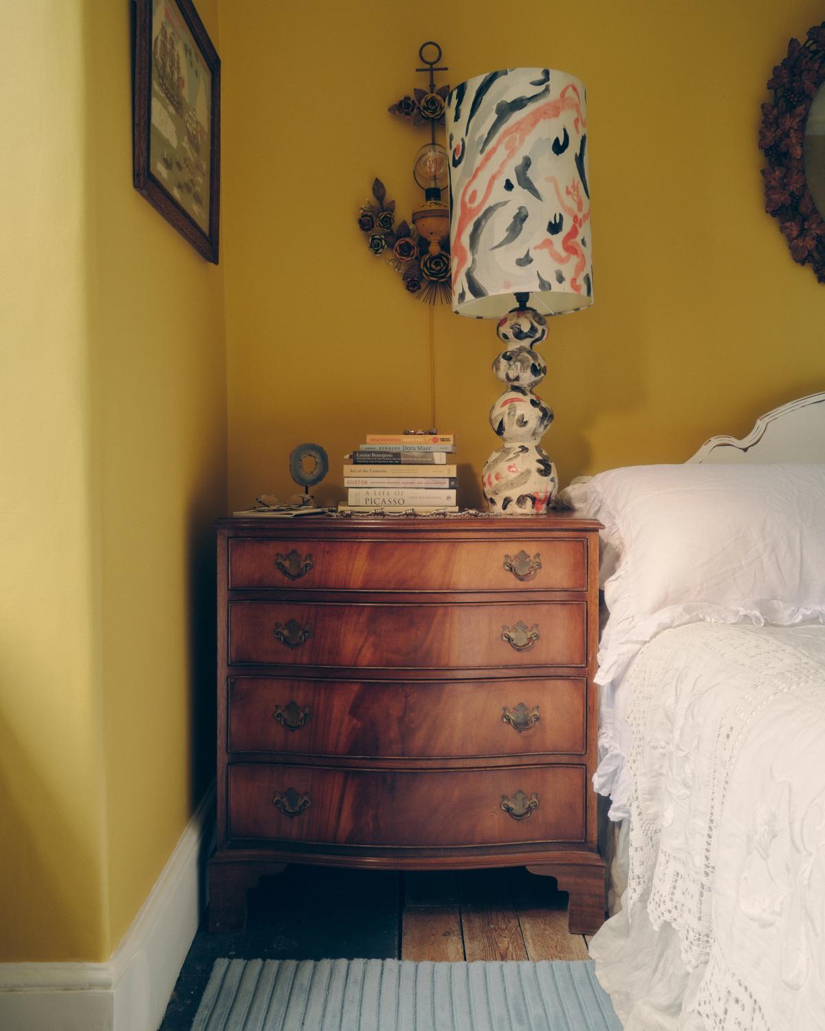 Plush wool rug Park 02 in Sky pictured by a wooden drawer nightstand in a bedroom with yellow walls.