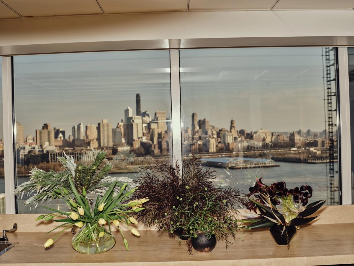 Tre vackra blomsterarrangemang visade i ett ljust fönster med utsikt över höghus i New York, USA.