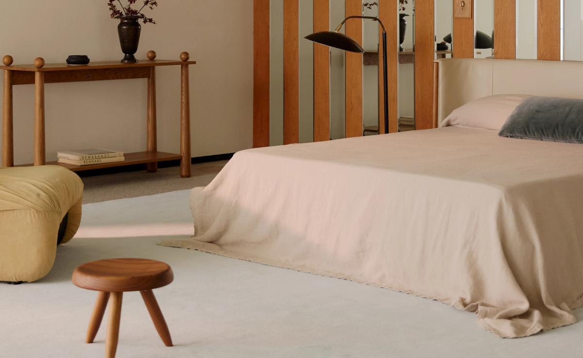 Grand-mattan i Powder Blue visas i ett minimalistiskt sovrum med mjuka neutrala toner, en låg pall i trä och skulpturala detaljer, vilket skapar en lugn och sofistikerad atmosfär.