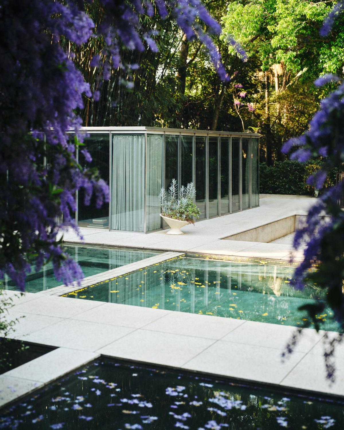 Ett modernistiskt paviljongliknande poolområde omgivet av frodig grönska, fotograferat i São Paulo, Brasilien, med speglande vattenytor och mjukt dagsljus.
